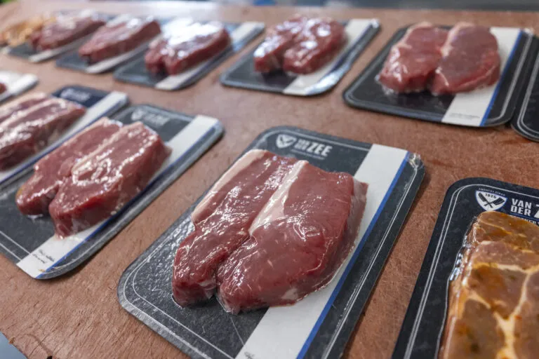 Vacuum-sealed steaks in recyclable cardboard trays for sustainable fresh meat packaging.