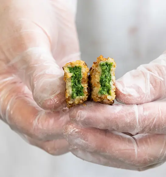 Breaded spinach finger cut open to show its spinach filling for industrial plant-based food production.